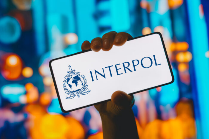 The International Criminal Police Organization (Interpol) logo is displayed on a smartphone screen