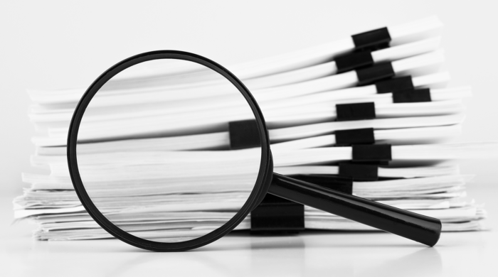 Magnifying glass inspecting a stack of papers